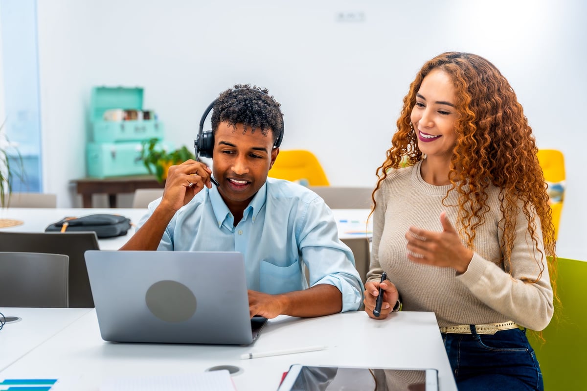 Two diverse coworkers collaborating in a bright modern office on customer service and teamwork